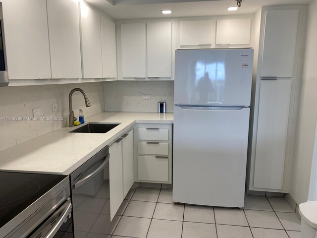 kitchen with light tile patterned floors, stainless steel appliances, white cabinetry, and sink