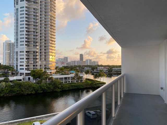 balcony at dusk featuring a water view