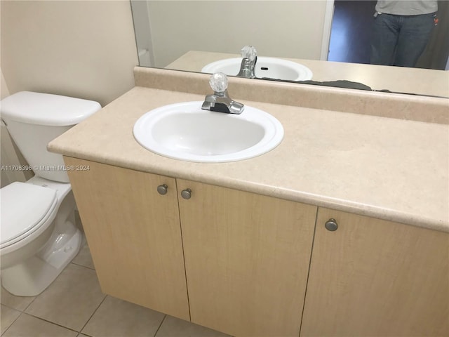 bathroom with toilet, vanity, and tile patterned floors