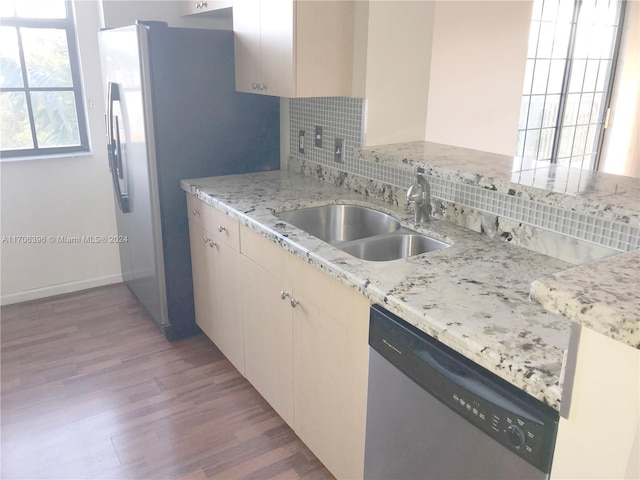 kitchen with dishwasher, backsplash, sink, light stone countertops, and light hardwood / wood-style floors