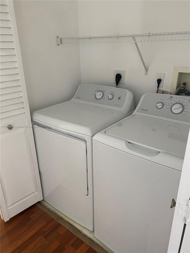 clothes washing area with separate washer and dryer and dark wood-type flooring