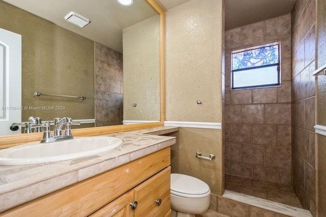 bathroom with vanity, toilet, and a tile shower