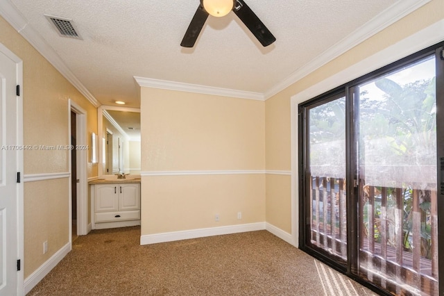 carpeted empty room with ceiling fan, ornamental molding, and a textured ceiling