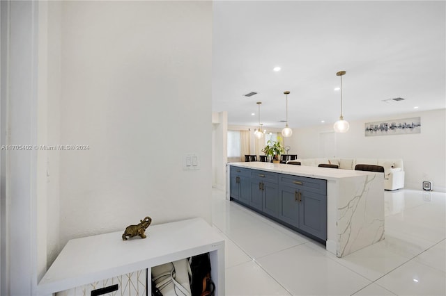 kitchen featuring a kitchen bar, pendant lighting, light tile patterned floors, and blue cabinets