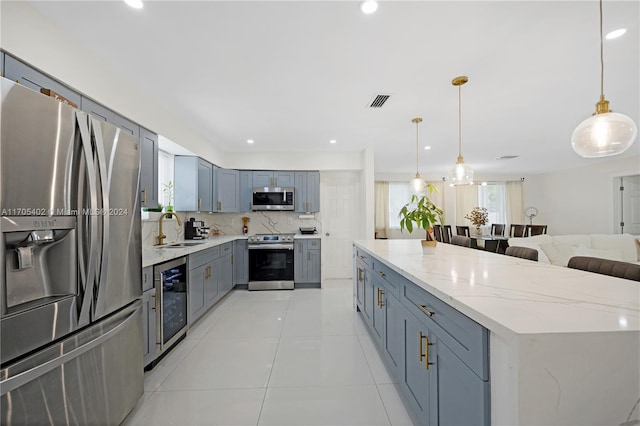 kitchen featuring sink, hanging light fixtures, decorative backsplash, light tile patterned flooring, and appliances with stainless steel finishes