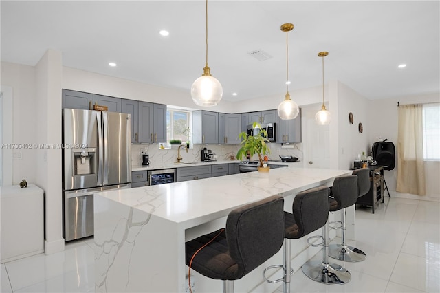 kitchen with a wealth of natural light, light stone counters, decorative light fixtures, and appliances with stainless steel finishes