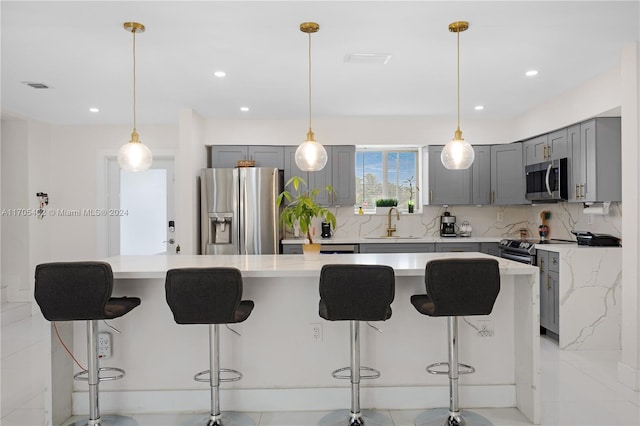 kitchen featuring a kitchen breakfast bar, stainless steel appliances, a kitchen island, and sink