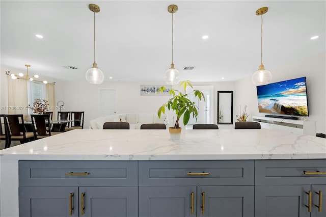 kitchen featuring light stone countertops, hanging light fixtures, and gray cabinetry