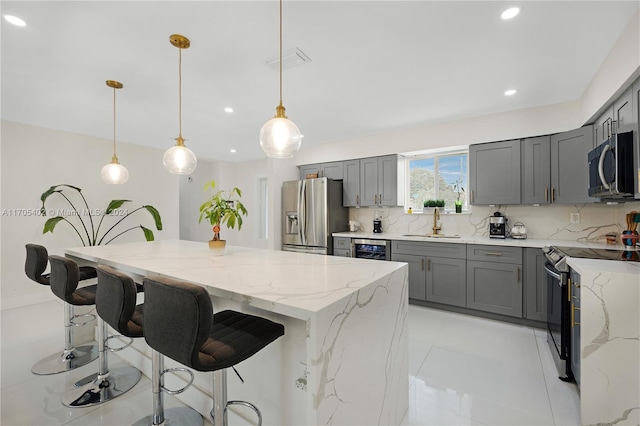 kitchen with sink, tasteful backsplash, decorative light fixtures, a kitchen island, and stainless steel appliances