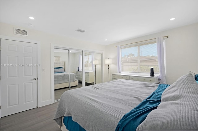 bedroom with light hardwood / wood-style flooring and multiple closets