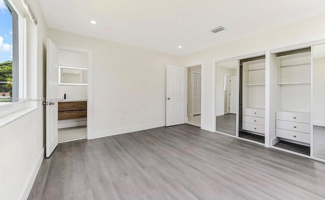 unfurnished bedroom featuring light hardwood / wood-style flooring and multiple closets