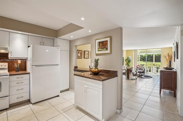 kitchen featuring white appliances, decorative backsplash, dark stone counters, light tile patterned flooring, and expansive windows