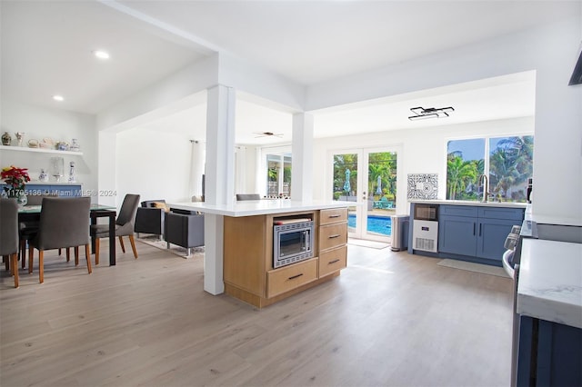 kitchen featuring a center island with sink, light hardwood / wood-style flooring, stainless steel microwave, and sink