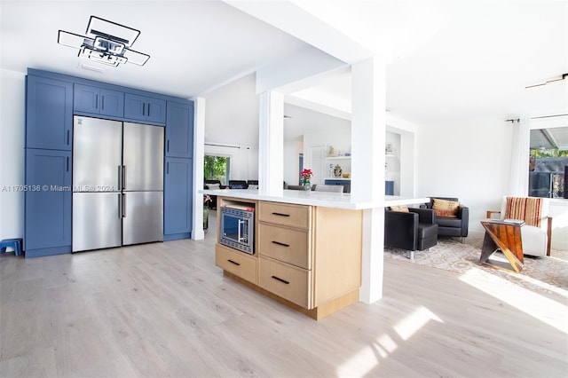 kitchen featuring appliances with stainless steel finishes, light brown cabinets, a kitchen island, and a wealth of natural light