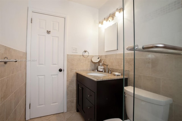 bathroom with tile patterned flooring, vanity, toilet, and tile walls