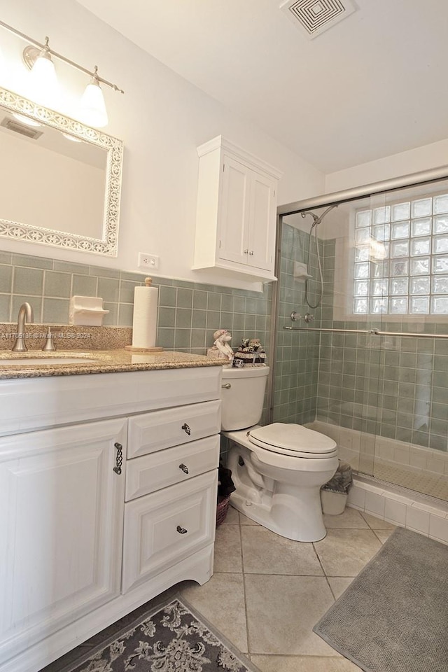 bathroom featuring tile patterned flooring, vanity, toilet, and walk in shower