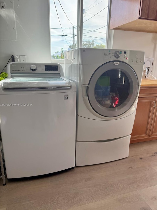 laundry room with cabinets, separate washer and dryer, and light hardwood / wood-style flooring