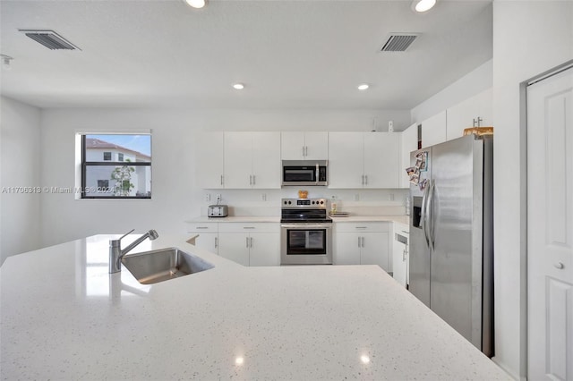 kitchen with stainless steel appliances, white cabinetry, and sink