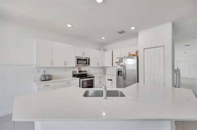 kitchen featuring sink, light tile patterned floors, appliances with stainless steel finishes, light stone counters, and white cabinetry