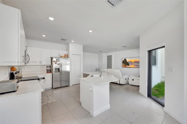 kitchen with stainless steel appliances, a kitchen island, sink, white cabinetry, and light tile patterned flooring