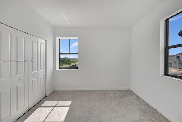 unfurnished bedroom with a closet and light colored carpet