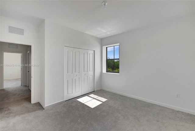 unfurnished bedroom with light carpet and a closet