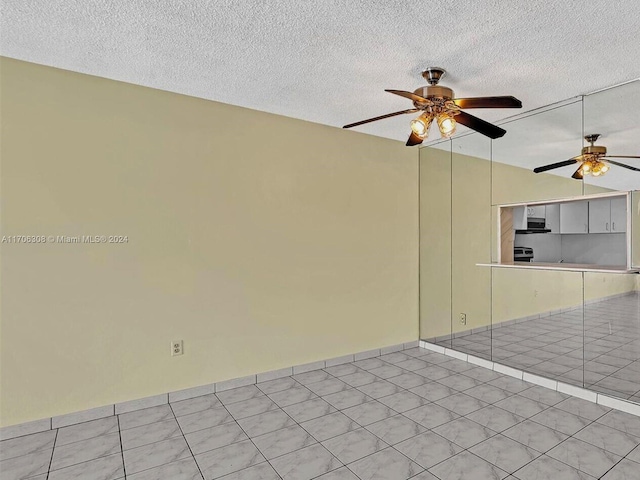 spare room featuring a textured ceiling, ceiling fan, and light tile patterned flooring