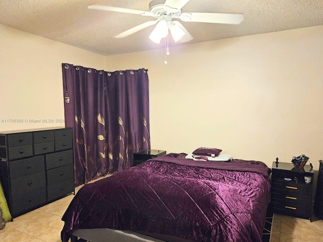 bedroom featuring ceiling fan, light tile patterned flooring, and a textured ceiling