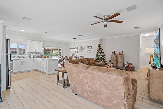 living room with light wood-type flooring, ceiling fan, and ornamental molding