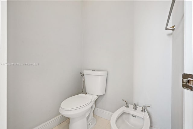 bathroom with toilet, tile patterned floors, and a bidet