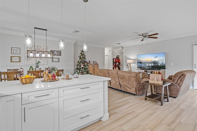 kitchen featuring light wood-type flooring, white cabinetry, hanging light fixtures, and crown molding