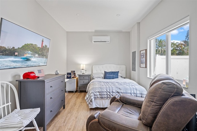 bedroom featuring a wall mounted AC and light hardwood / wood-style floors