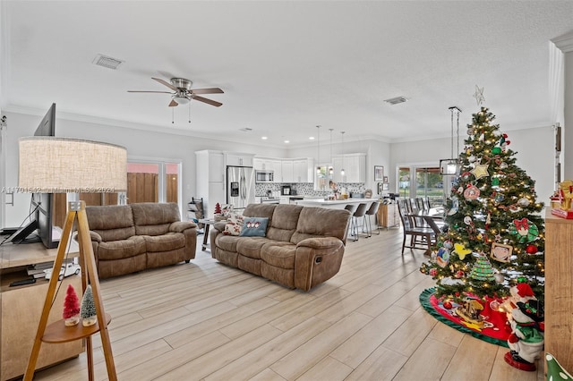 living room with ceiling fan, light wood-type flooring, and ornamental molding