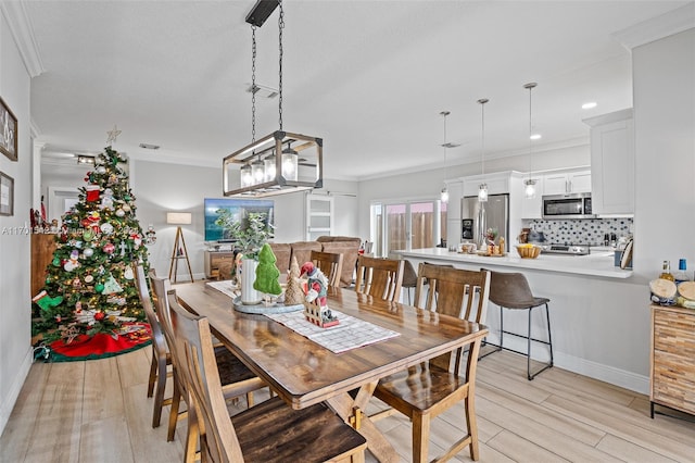 dining space featuring light wood-type flooring and crown molding