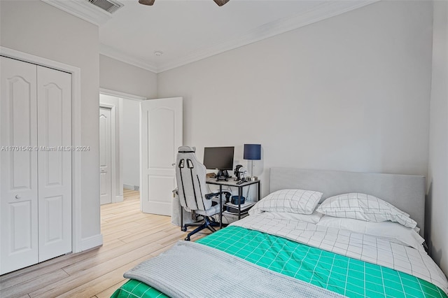 bedroom with light hardwood / wood-style floors, a closet, ornamental molding, and ceiling fan