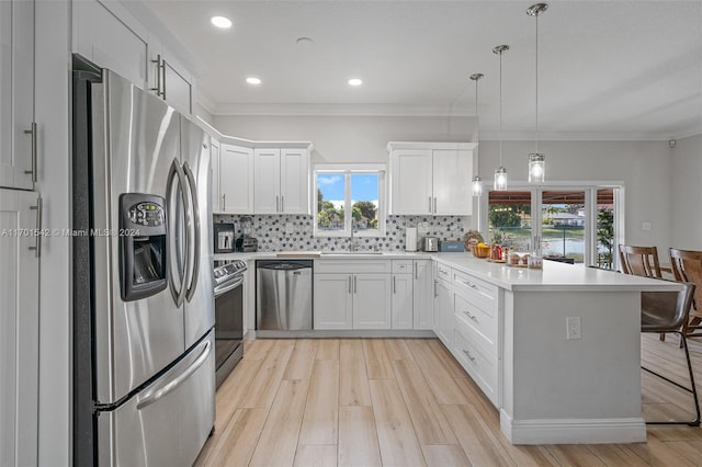 kitchen with pendant lighting, a healthy amount of sunlight, white cabinets, and stainless steel appliances