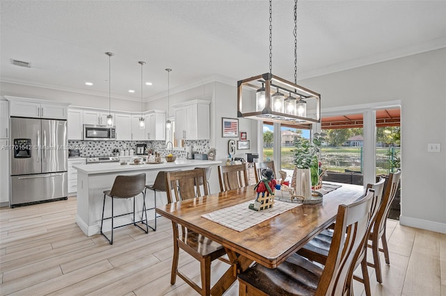 dining area with light hardwood / wood-style floors and ornamental molding