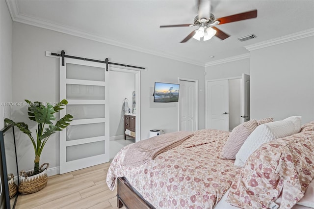 bedroom featuring a barn door, ceiling fan, ornamental molding, and light wood-type flooring