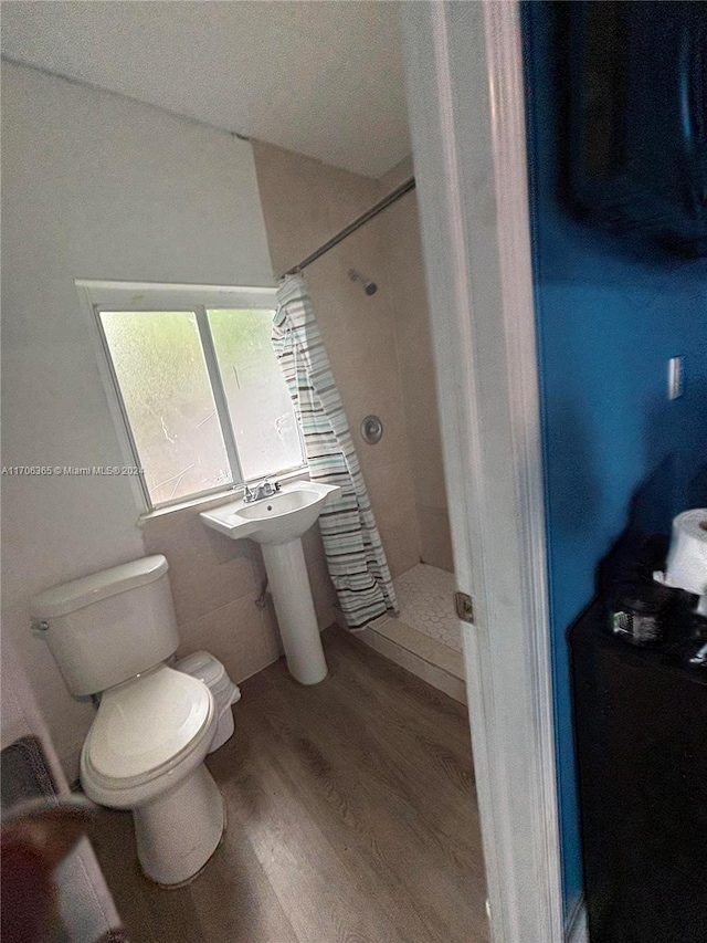 bathroom featuring tiled shower, sink, wood-type flooring, and toilet