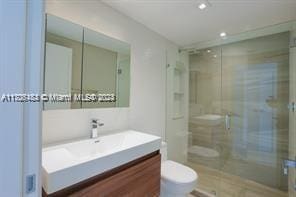 bathroom featuring an enclosed shower, vanity, and toilet