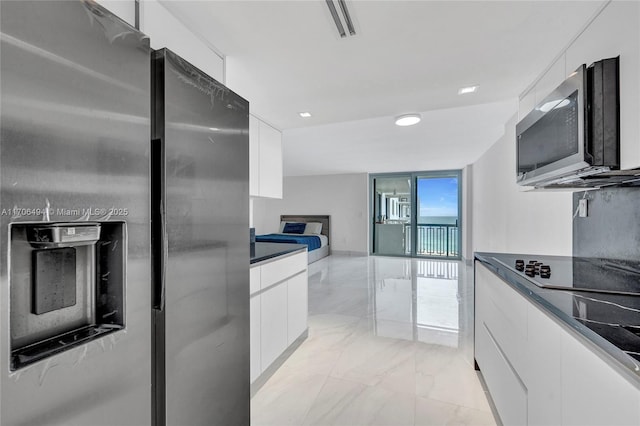 kitchen with stainless steel appliances, white cabinetry, and floor to ceiling windows