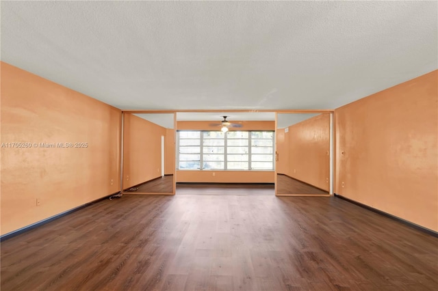 empty room featuring a textured ceiling, dark wood-type flooring, and baseboards