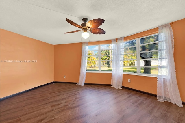 empty room with a ceiling fan, a textured ceiling, baseboards, and wood finished floors