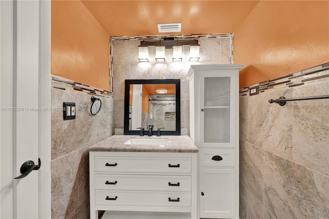 bathroom featuring visible vents, tile walls, and vanity