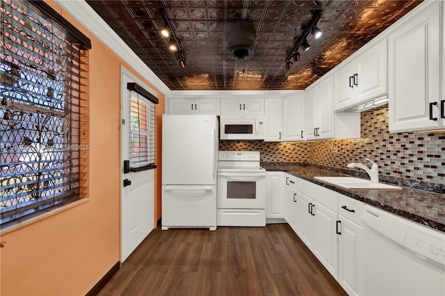 kitchen featuring white appliances, a sink, white cabinets, backsplash, and dark stone countertops