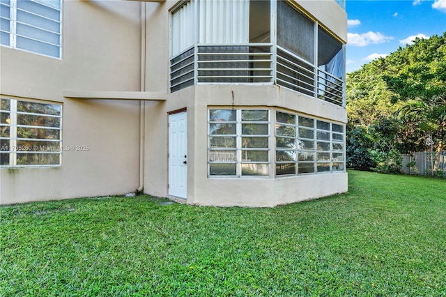 view of exterior entry featuring a lawn and stucco siding