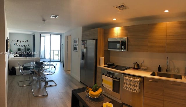 kitchen with sink, stainless steel appliances, and light wood-type flooring