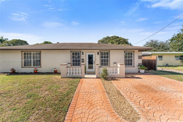 ranch-style home featuring covered porch and a front yard