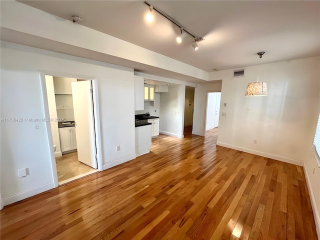 unfurnished living room featuring light wood-type flooring and rail lighting