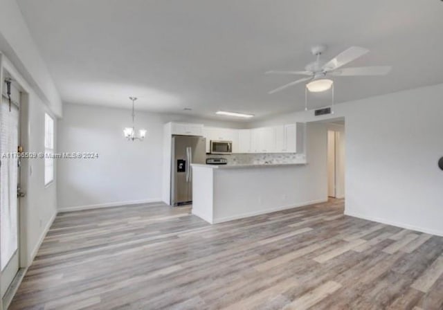 unfurnished living room featuring ceiling fan with notable chandelier and light wood-type flooring